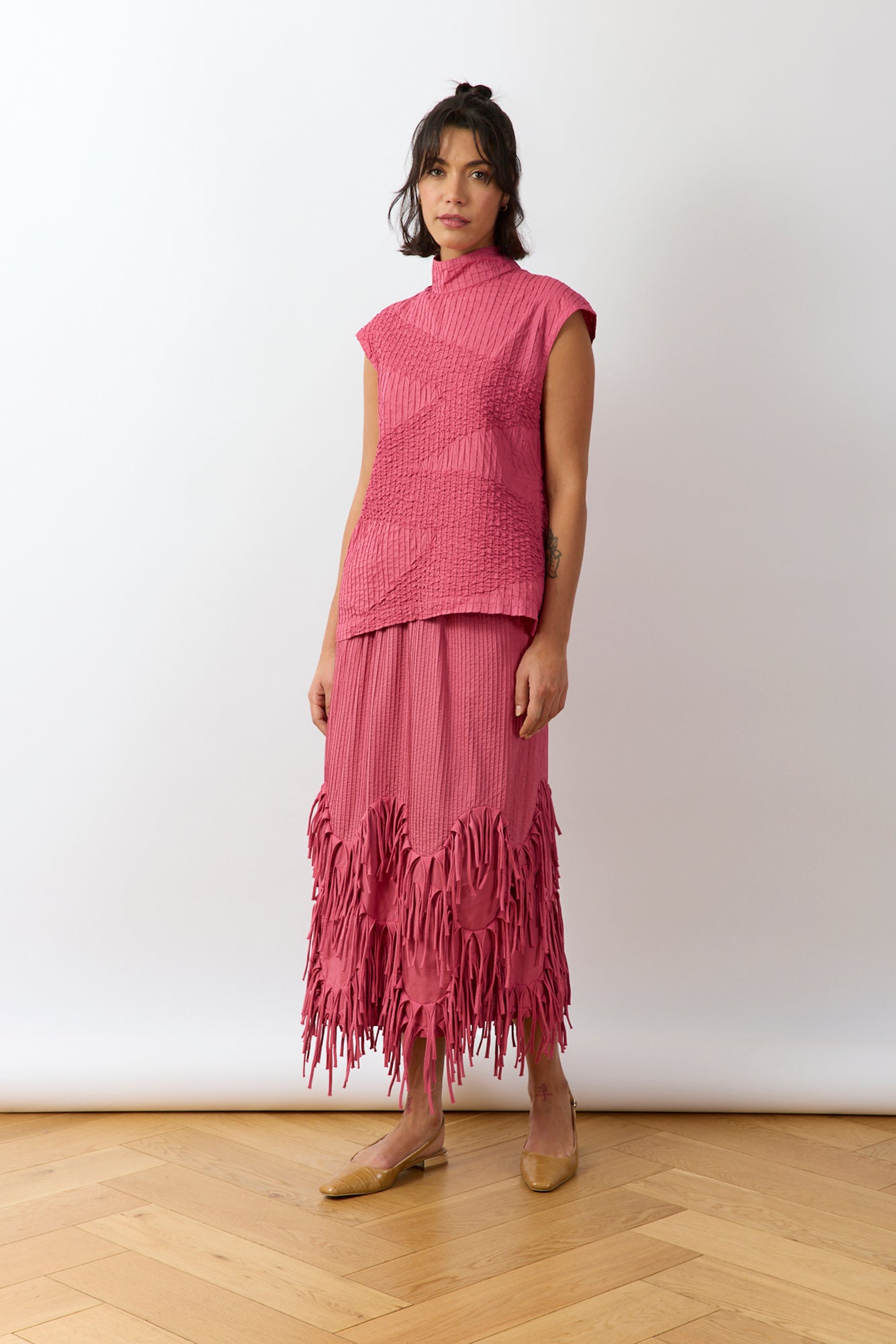 Kazari Skirt in Dust Rose slight angle view showing textured panels and fluid shape.