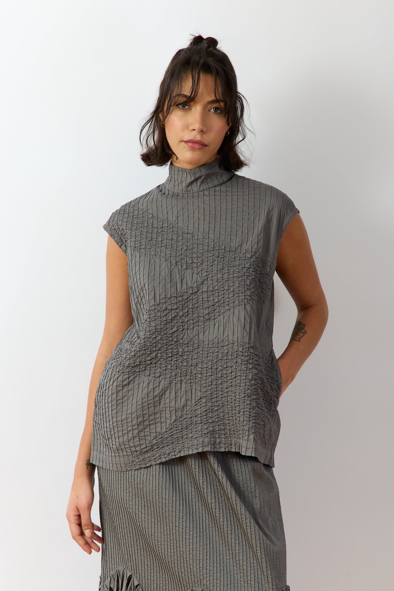 Front view of the YaccoMaricard Shibo Shell Top 1091573 in Ash, showing the longline "off-body" silhouette, high turtle neckline, and signature textured pintuck and smock stitching.