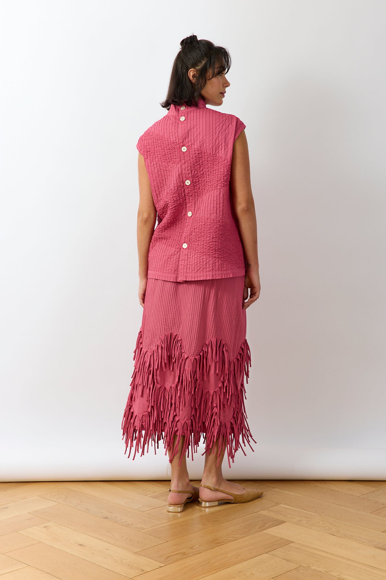 Back view of Dust Rose Kazari Skirt highlighting tailored construction and hem detail.