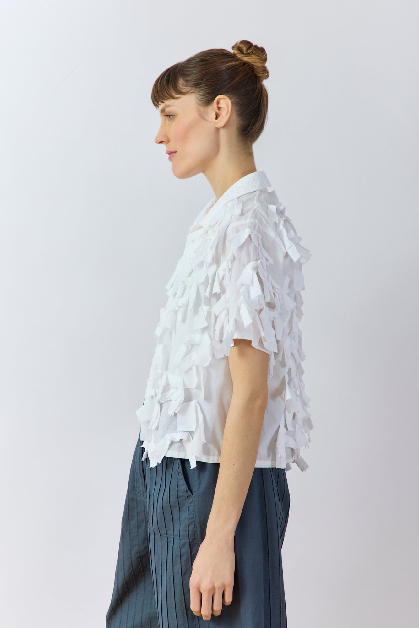Side view of white Yaccomaricard Hane Shirt showing sculptural raw-edge ribbon texture.