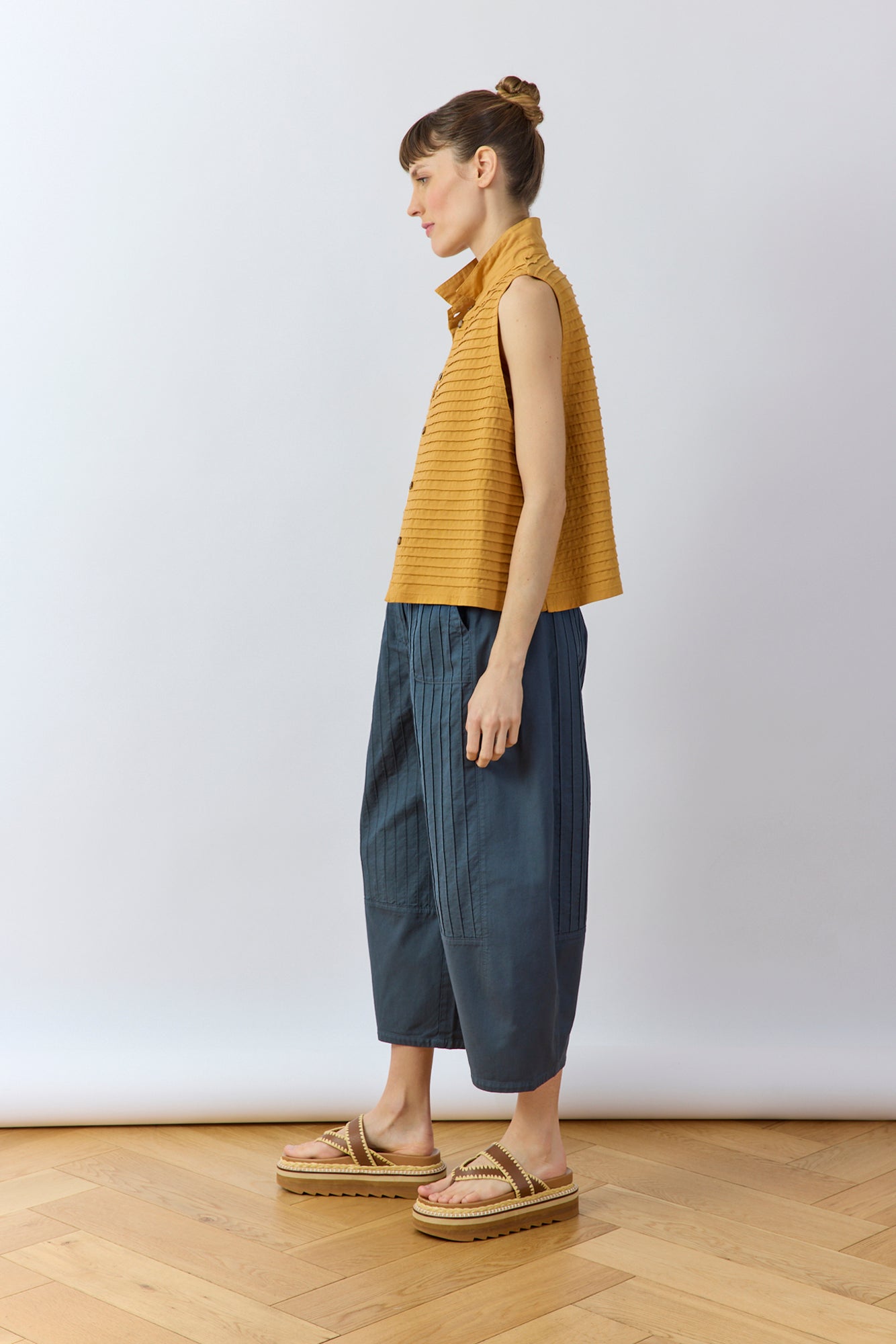 Side profile of the Stone Blue Obaru Trouser showing the architectural three-panel construction and contoured fit.