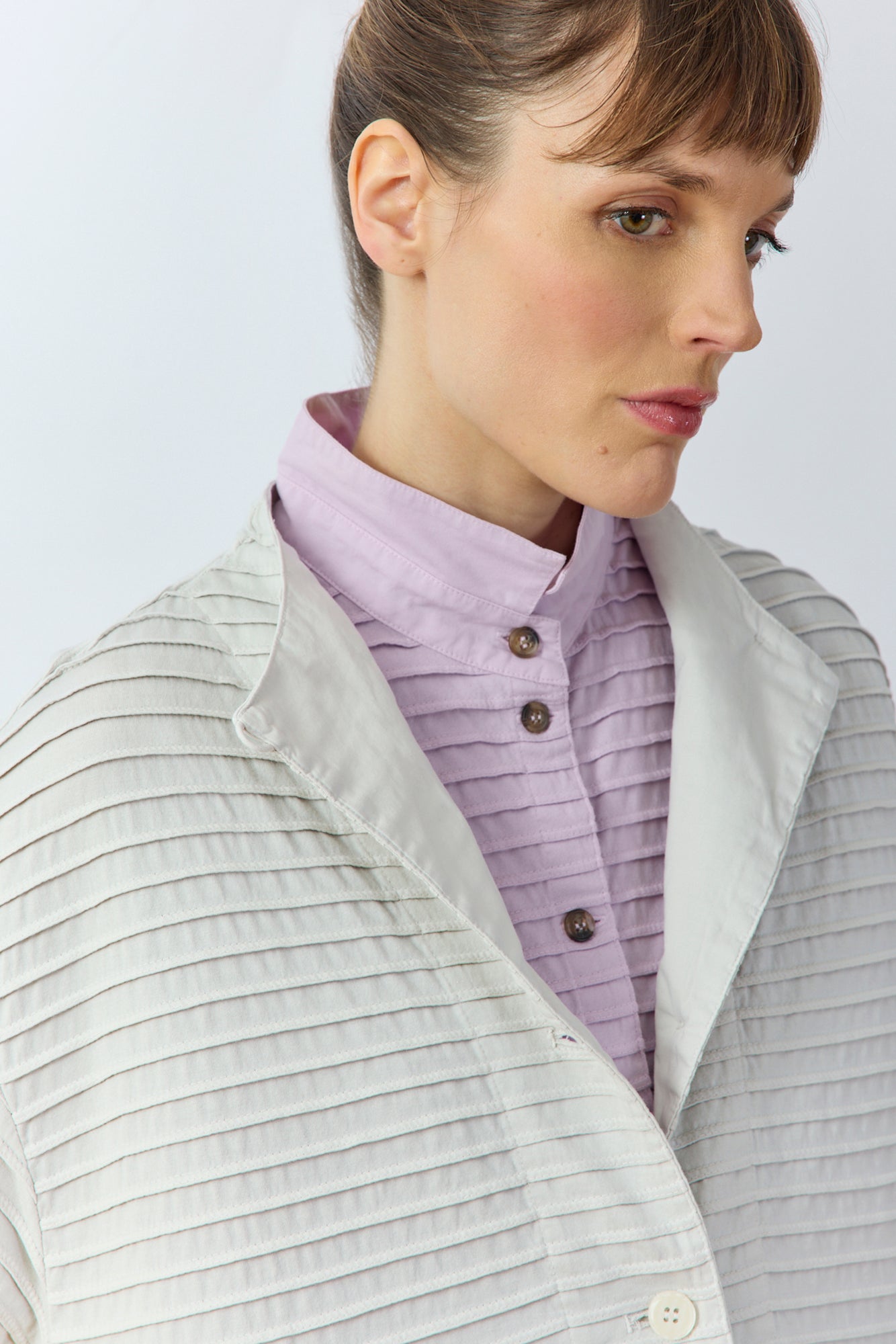 Close-up of the softly funnelled neckline and soft cotton jersey on the Yaccomaricard Faneru Jacket in cool grey.