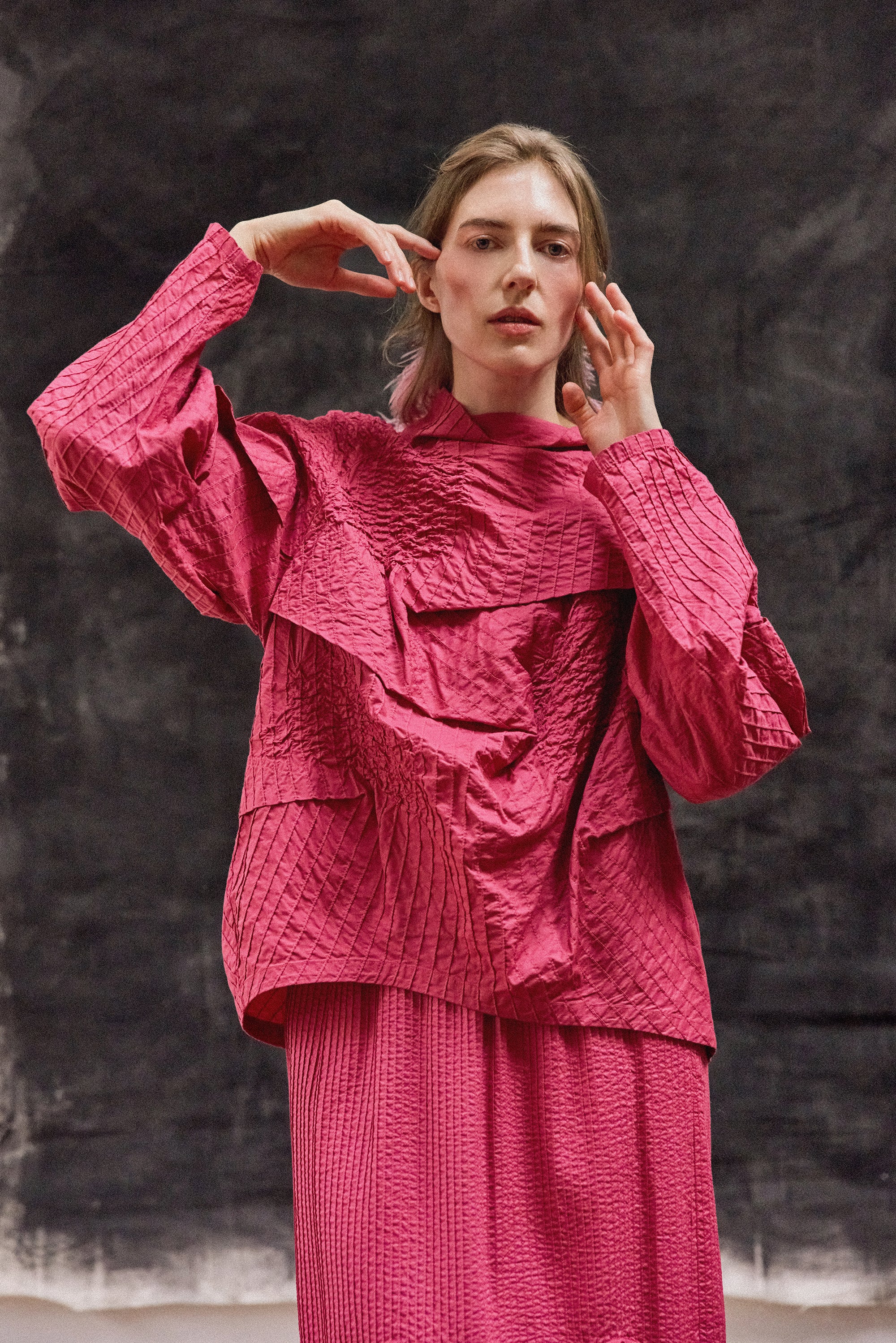 A lifestyle image of a model wearing the Yaccomaricard 1023998 Shibo top in Dust Rose, showcasing a contemporary, tonal Japanese-inspired aesthetic.